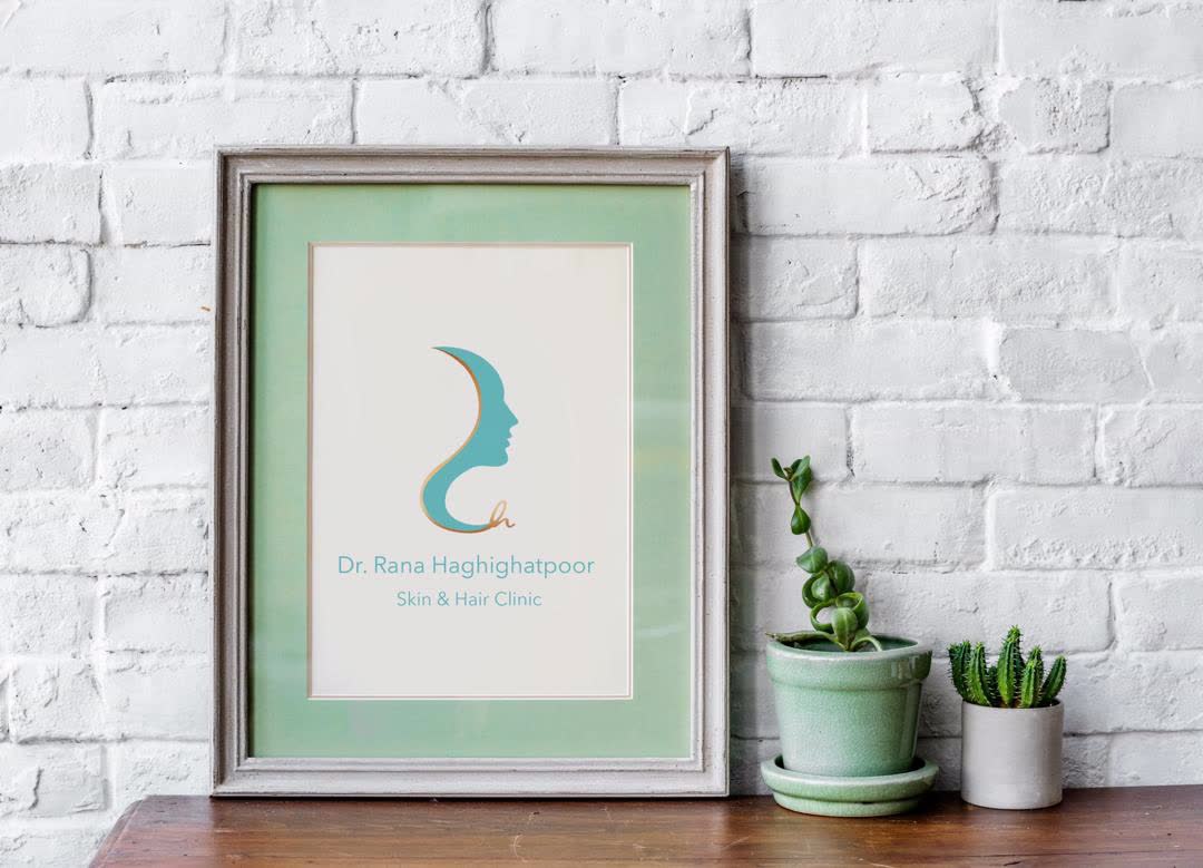 Framed clinic logo on a white brick wall beside succulents.