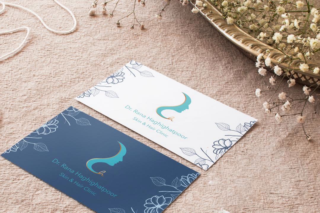 Light and dark business cards for the clinic on dusty-rose fabric.
